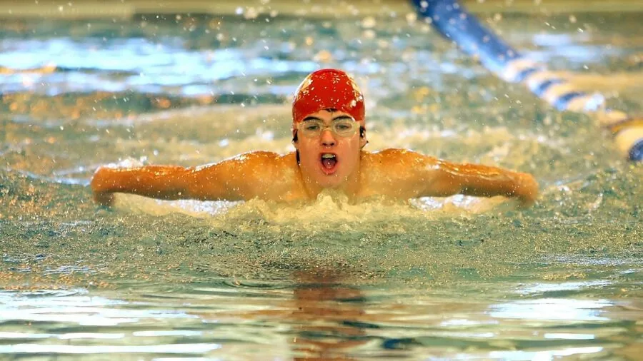 Swimmer doing freestyle stroke in clear pool water during fitness training session