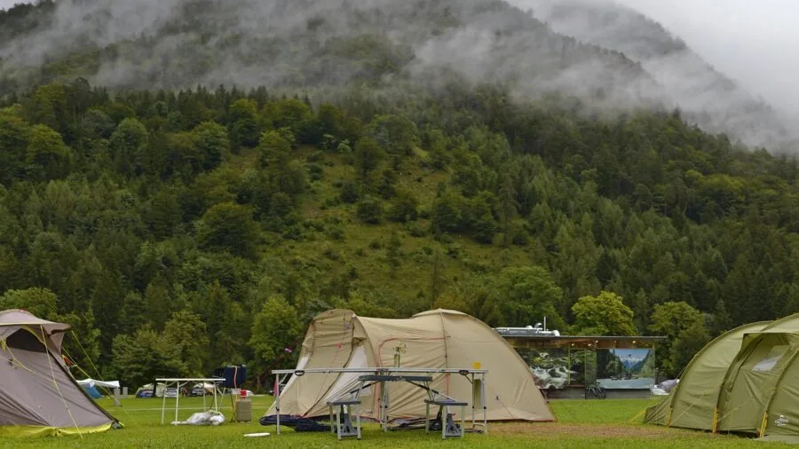 Tent setup in rainy camping conditions with water droplets and stormy sky