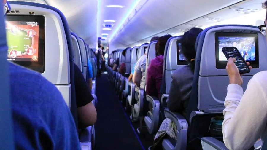 Traveler enjoying music with headphones during flight, looking out airplane window