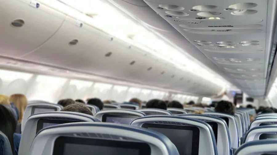 Traveler wearing headphones on airplane, experiencing peaceful flight environment