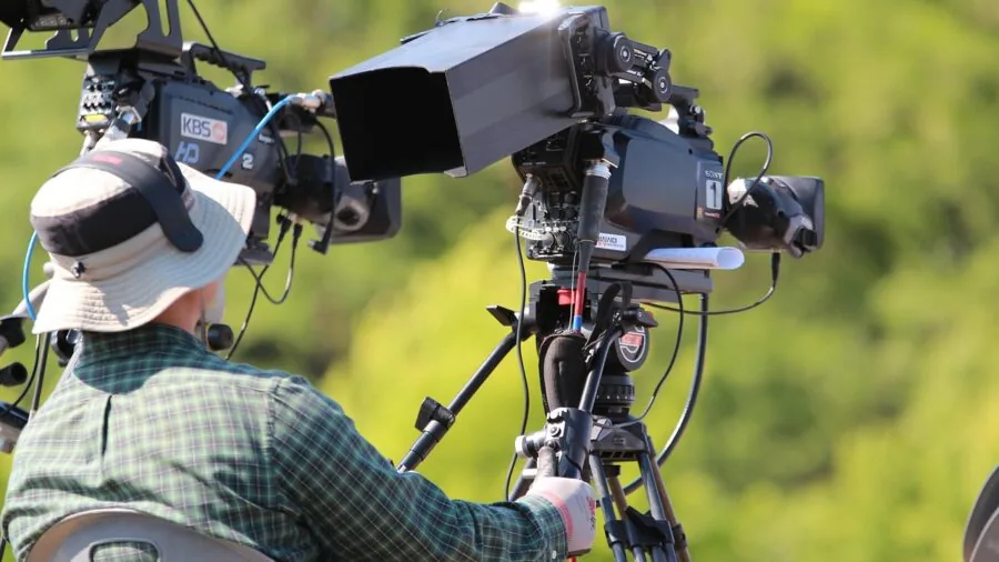 Videographer capturing outdoor event with continuous recording setup in natural daylight