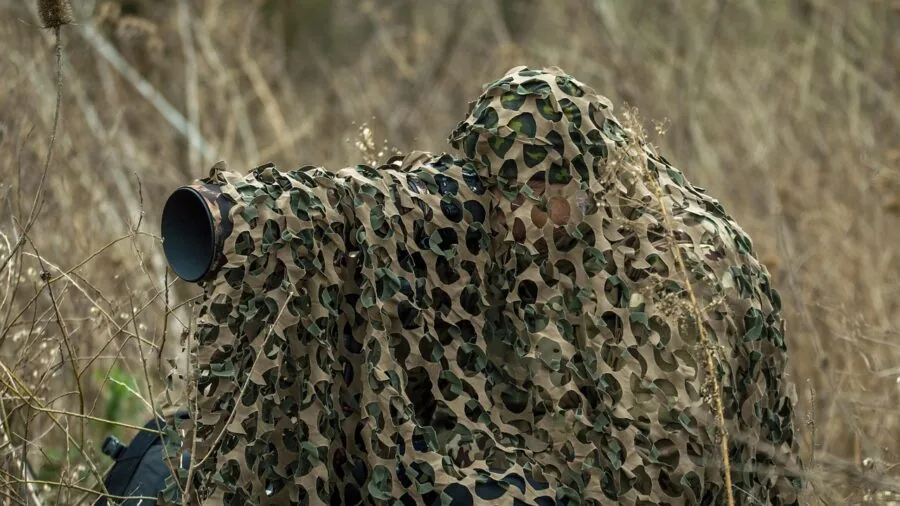 Wildlife photographer holding long telephoto lens in natural outdoor setting