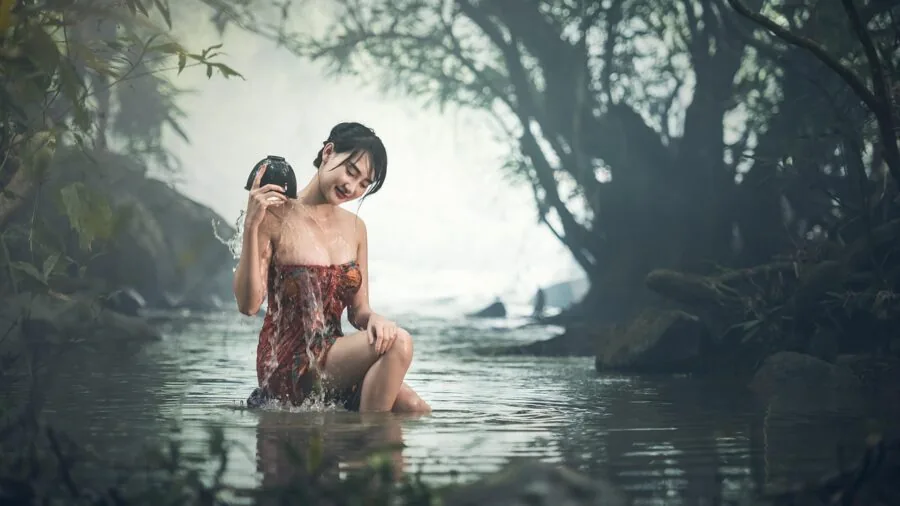 Woman rinsing hands under running water with water droplets splashing, demonstrating water resistance in daily life