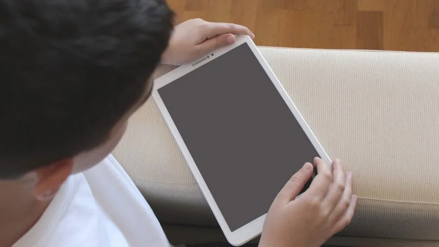 Young child accidentally dropping electronic tablet device onto hardwood floor at home