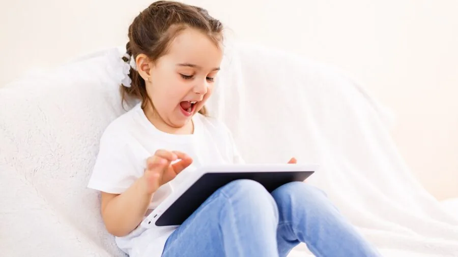 Young child engaged with digital learning on tablet device in natural home setting