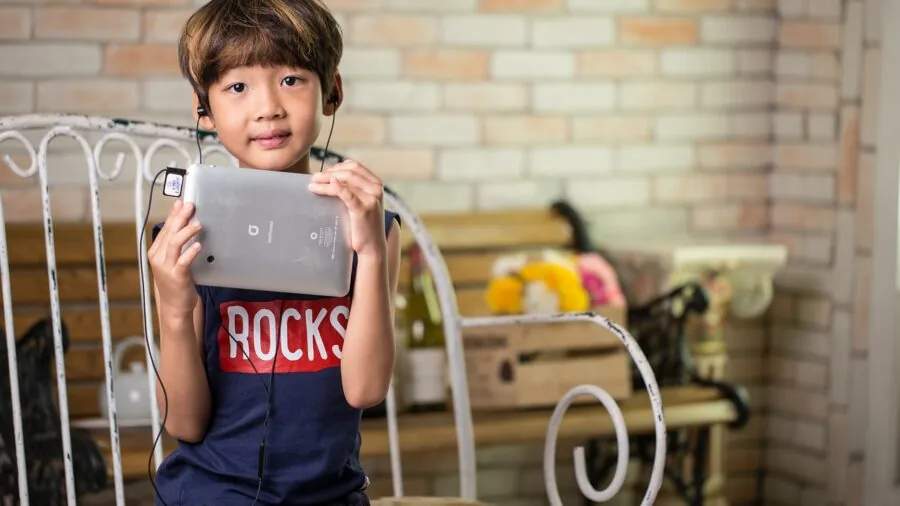 Young child enjoying music with wireless earbuds in a safe, comfortable outdoor setting