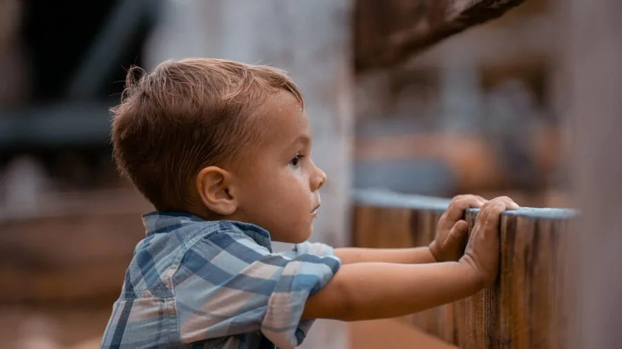Young child enthusiastically looking at smartphone screen while playing outside in natural daylight