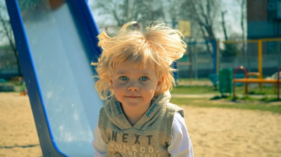 Young child playing energetically outdoors, demonstrating the need for durable gear for active toddlers