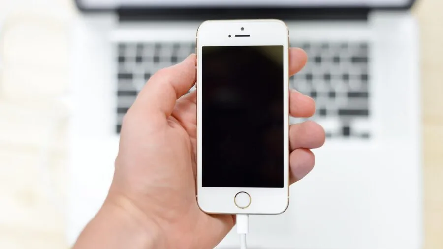 Young child plugging smartphone into charger while sitting at table