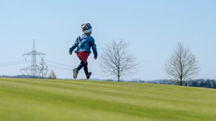 Young child running outdoors in natural daylight, capturing dynamic movement and action