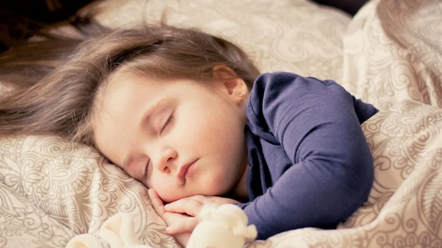Young child sleeping soundly in bed, representing health monitoring and sleep tracking features for kids smartwatches