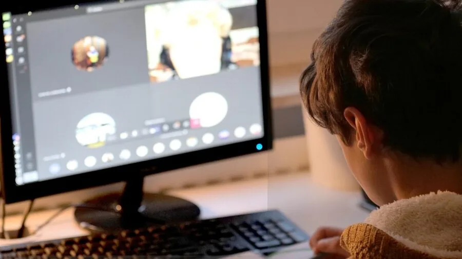 Young child wearing headphones during a video call on laptop for remote learning